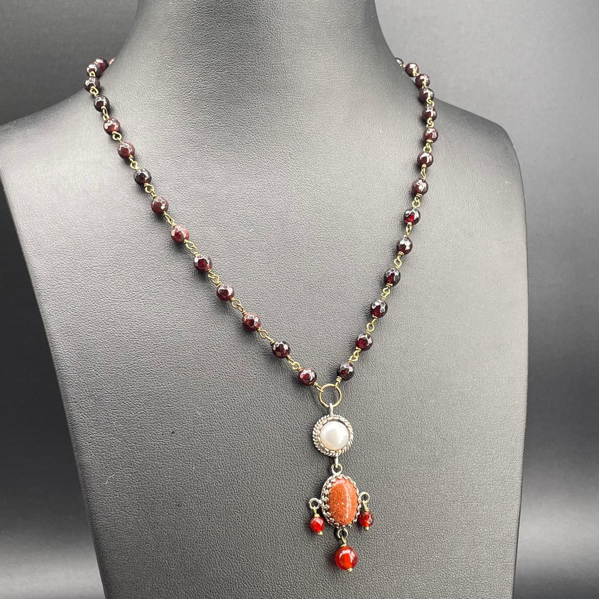 Collana BonBon in granati con pendente arancio e dettagli rossi, vista obliqua