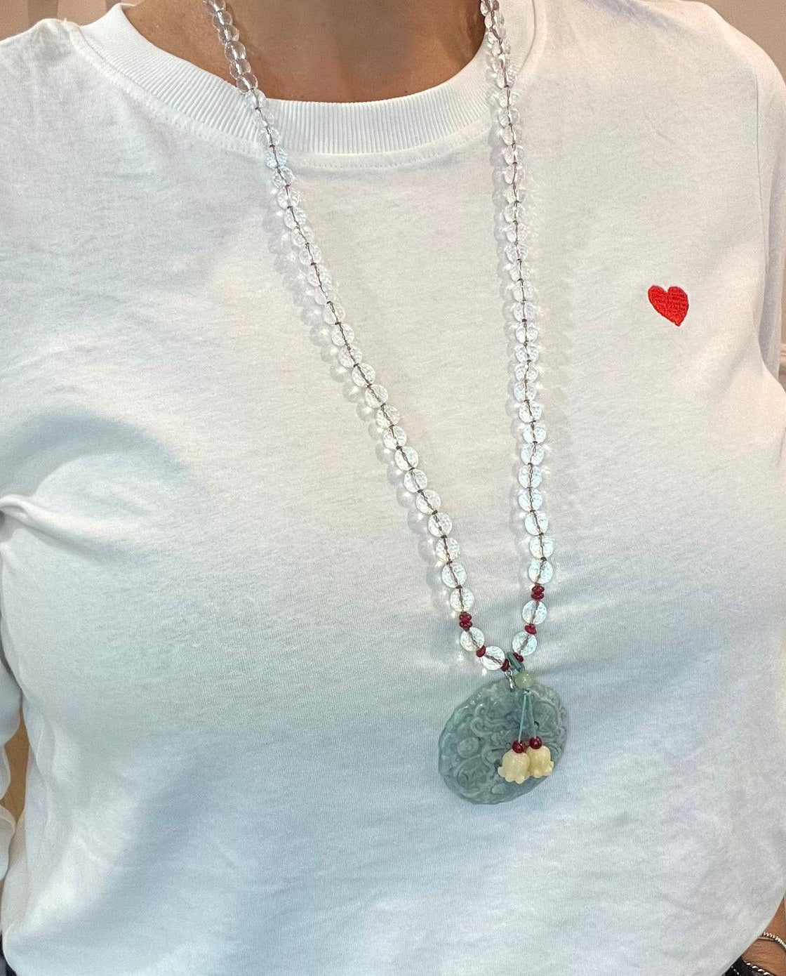 Collana lunga in cristallo di rocca con drago in giada indossata su maglia bianca