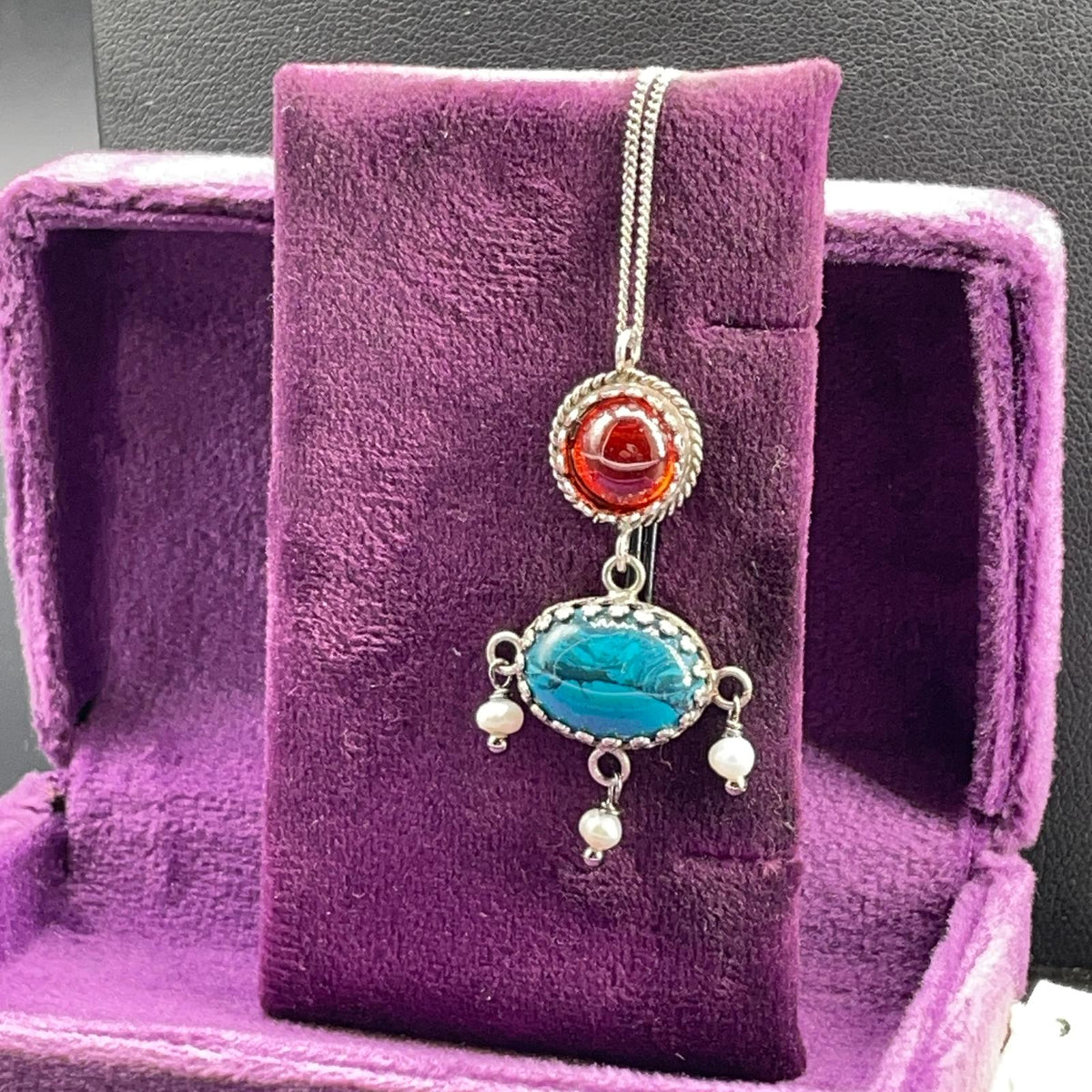 Pendente BonBon artigianale in argento 925 esposto su velluto viola, vista frontale