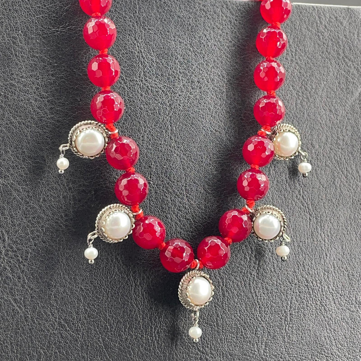 Particolare dei pendenti con perle coltivate bianche della collana in agata rossa
