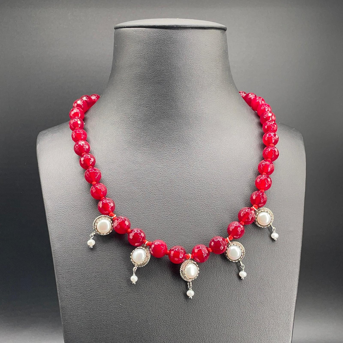 Collana BonBon in agata rossa sfaccettata e perle coltivate, vista frontale su busto nero