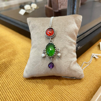 Pendente BonBon in argento 925 con pietre colorate e perle coltivate, dettaglio su cuscino chiaro