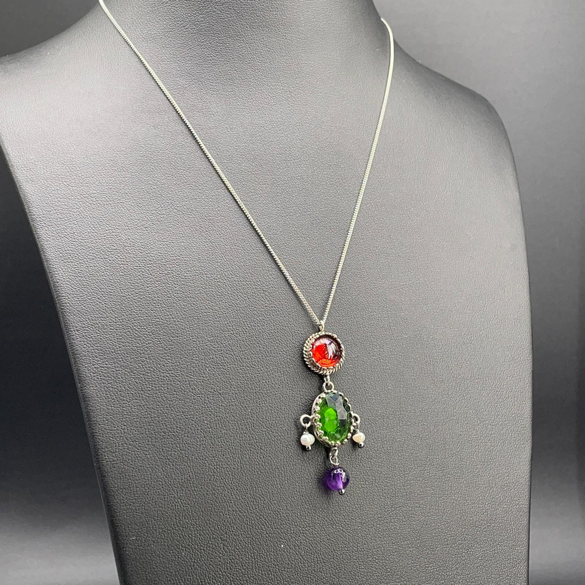 Collana BonBon in argento 925 con pietra verde ovale, elementi rossi e viola e perle coltivate su busto nero