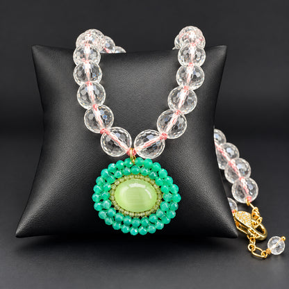 Collana di cristallo di rocca sfaccettato con pendente verde, vista distesa su fondo scuro
