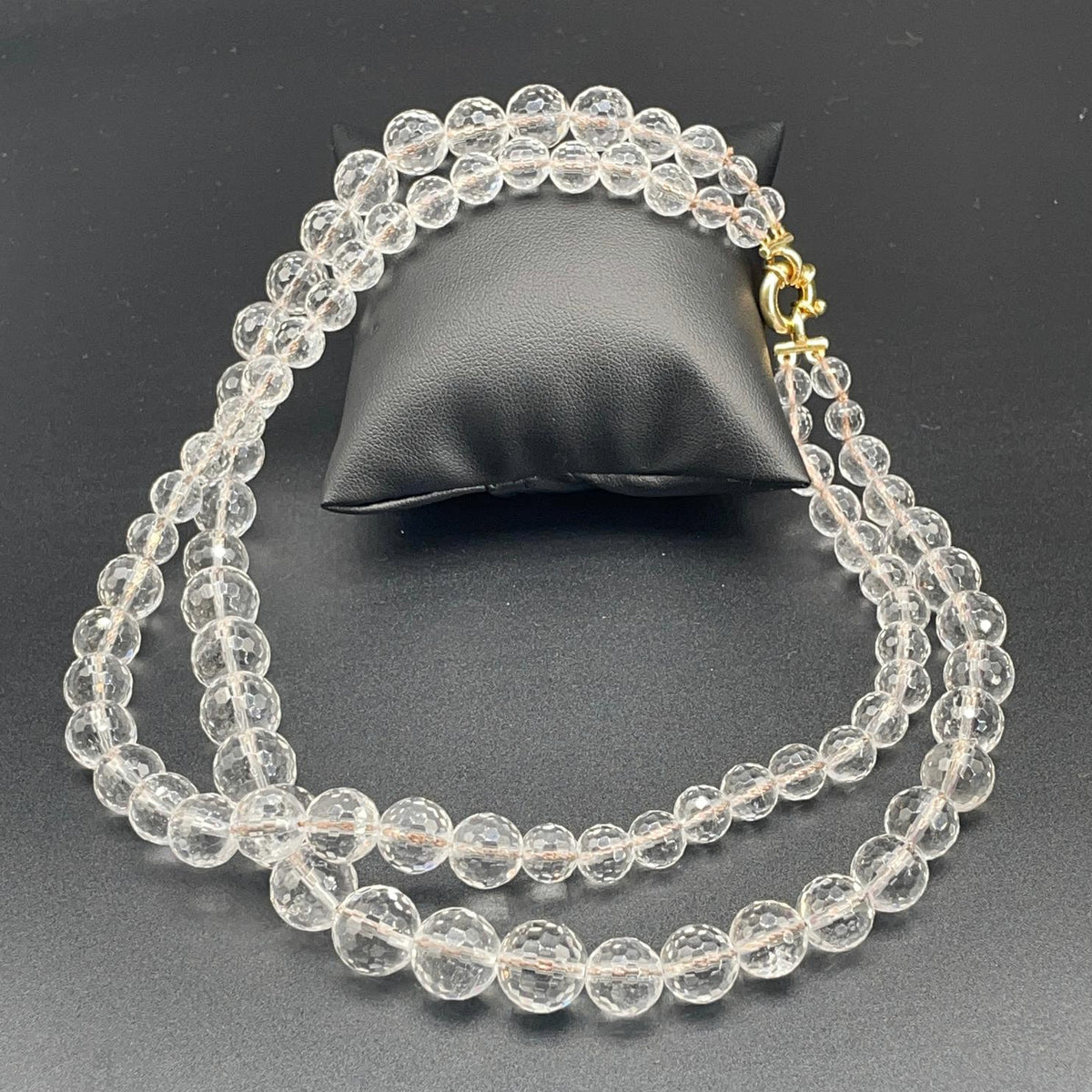 Collana a due fili in cristallo di rocca sfaccettato disposta su fondo scuro per mostrare entrambe le lunghezze