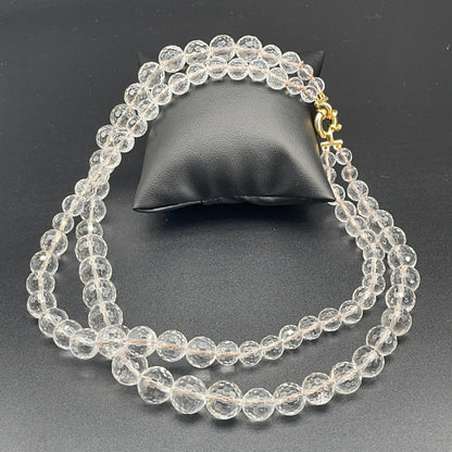 Collana a due fili in cristallo di rocca sfaccettato disposta su fondo scuro per mostrare entrambe le lunghezze