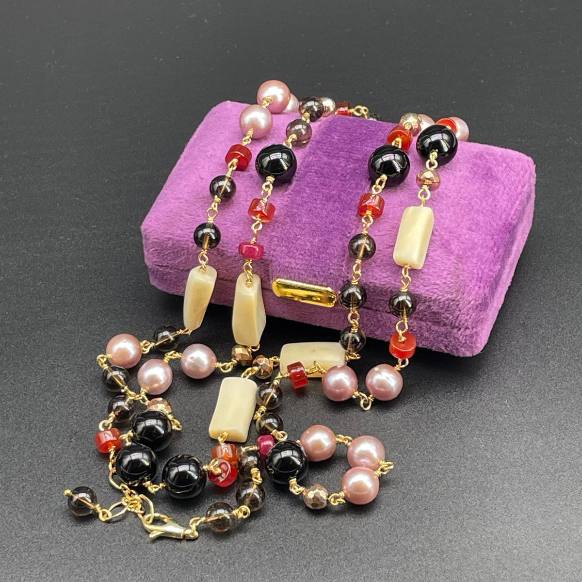 Collana artigianale lunga con pietre multicolori, fotografata distesa