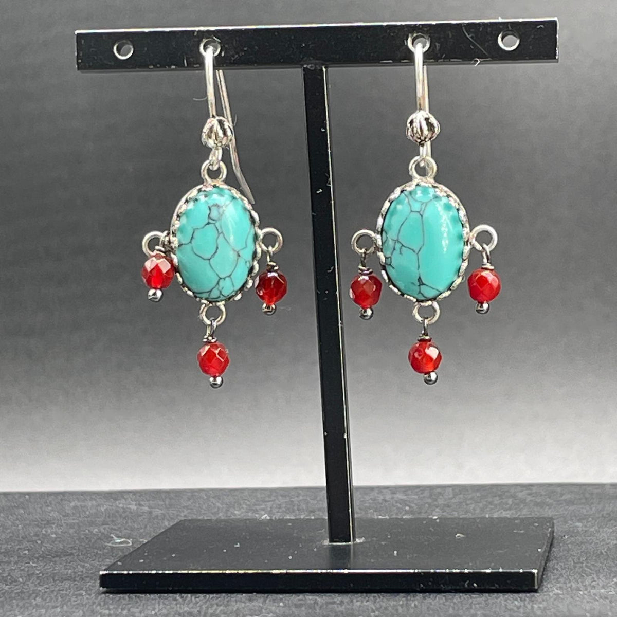 Orecchini BonBon in argento 925 con pietre ovali color turchese venate e pendenti rossi, vista frontale