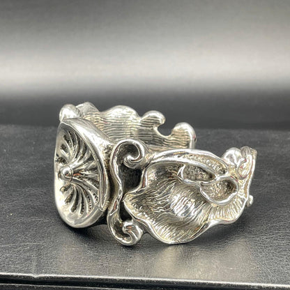 Dettaglio laterale del bracciale rigido in argento con decori floreali e volute in rilievo