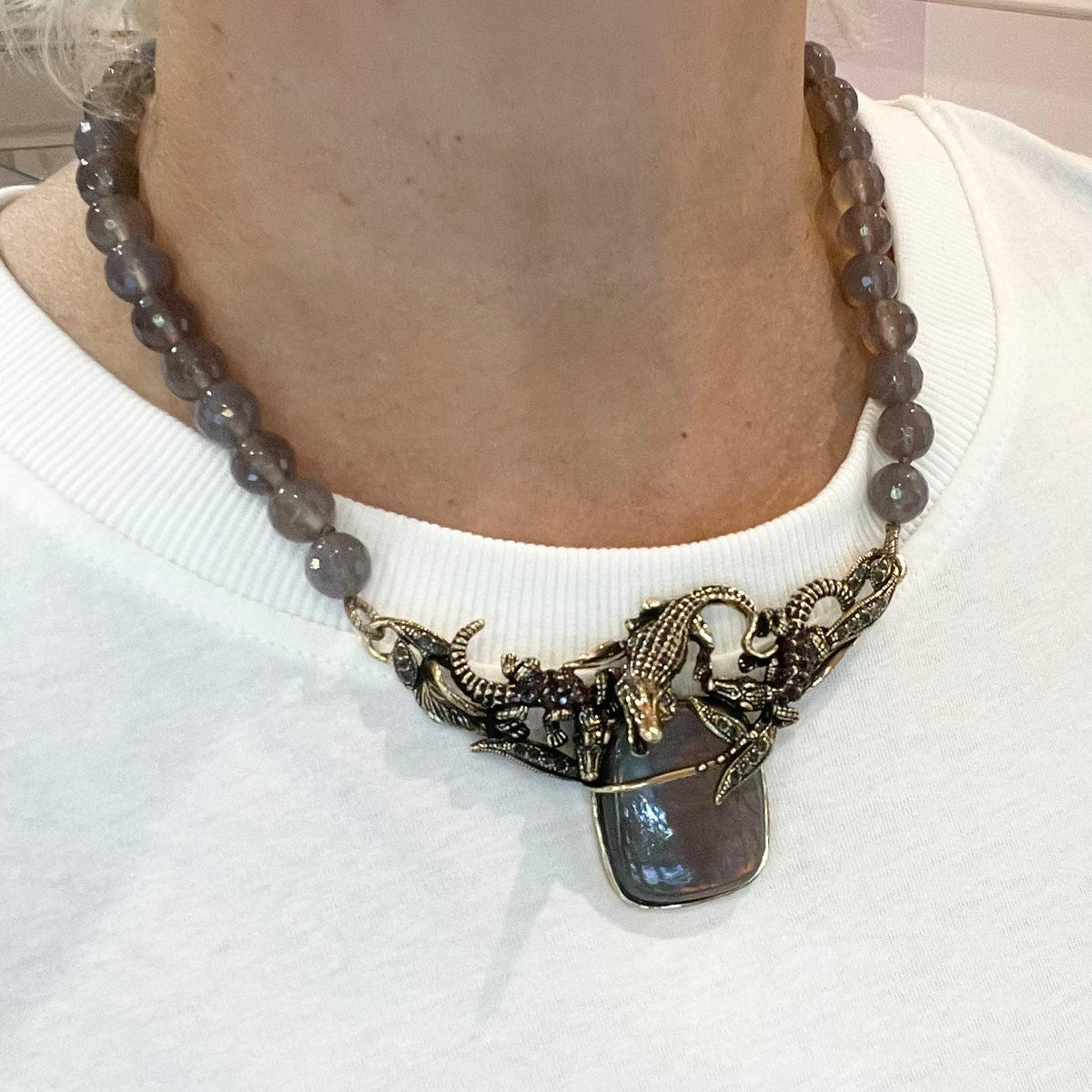 Collana in agata grigia con labradorite e coccodrilli, indossata su maglia bianca