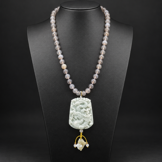 Collana lunga in agata grigia sfaccettata con pendente in giada intagliata a drago, vista frontale su busto nero