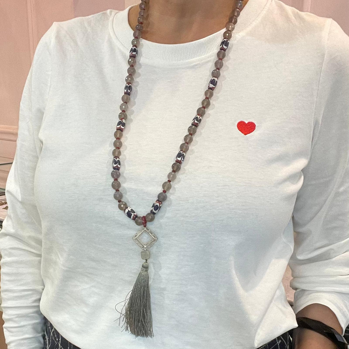 Collana lunga in agata e vetro artigianale indossata, con pendente filigranato e nappina