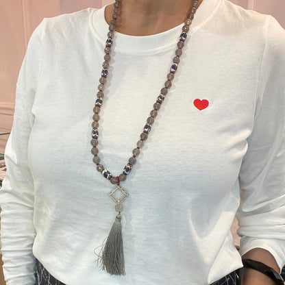 Collana lunga in agata e vetro artigianale indossata, con pendente filigranato e nappina