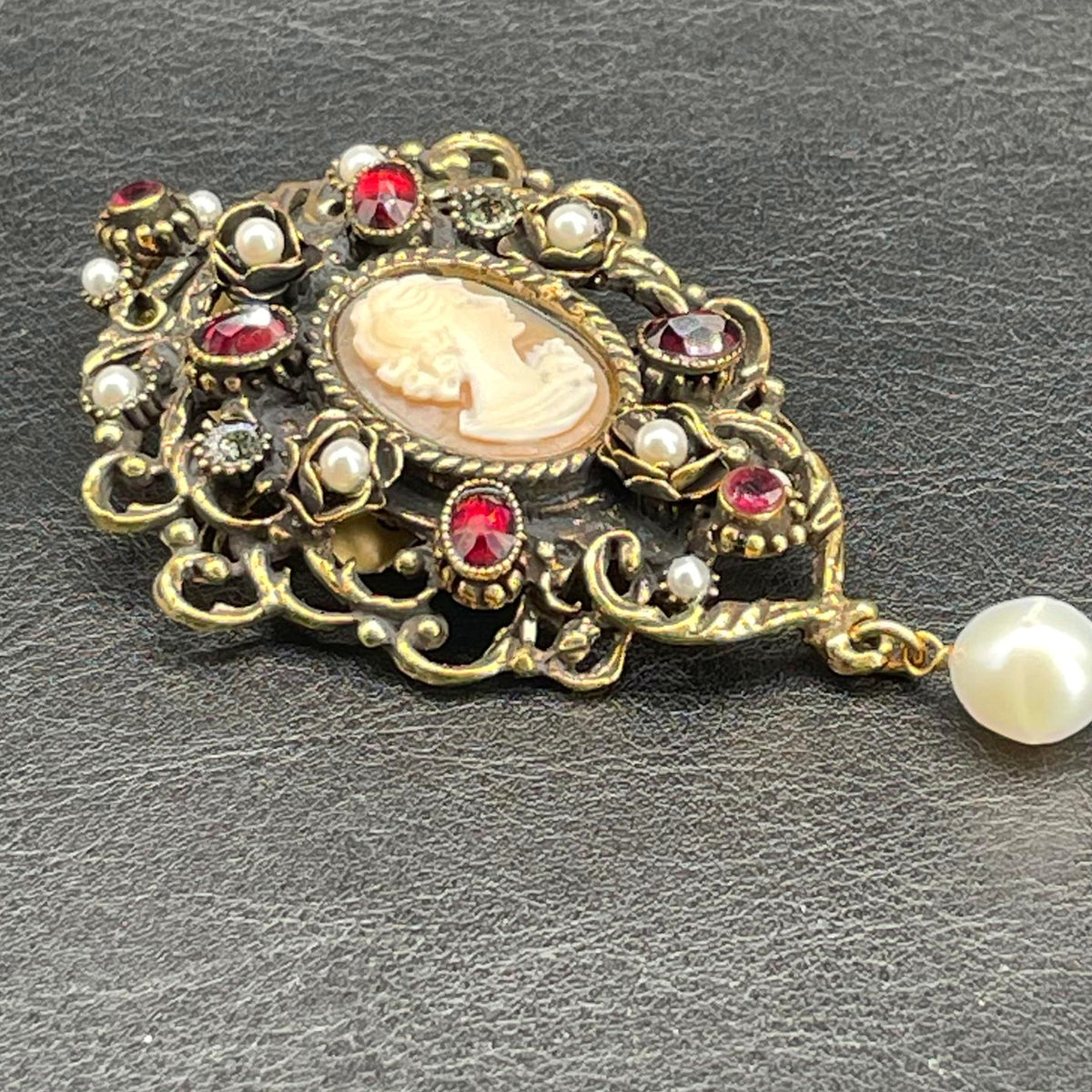 Dettaglio del cammeo centrale e delle decorazioni in ottone dorato con granati, perle e Swarovski della spilla Alcozer
